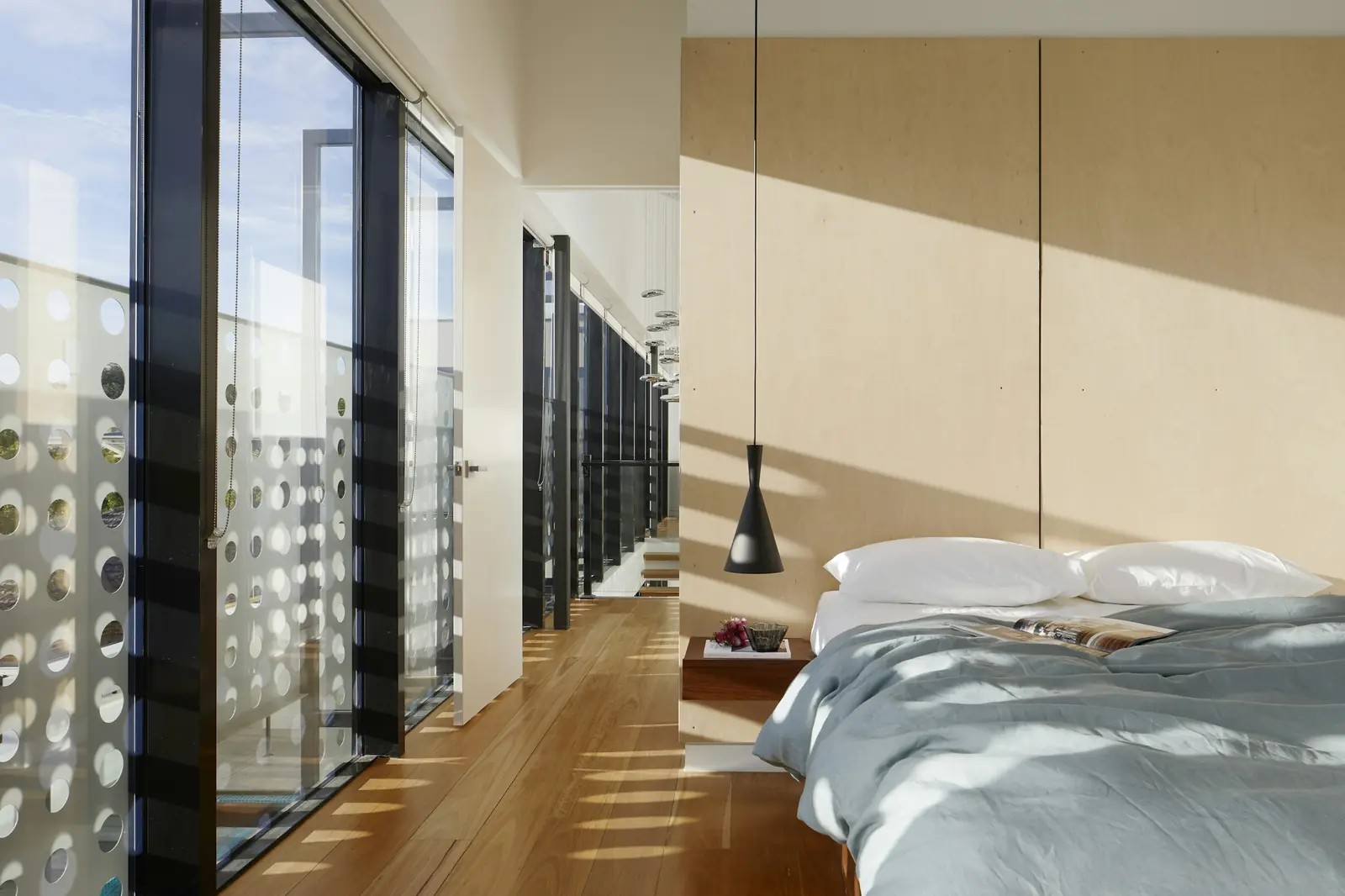 A bedroom with floor-to-ceiling glass and soft daylight