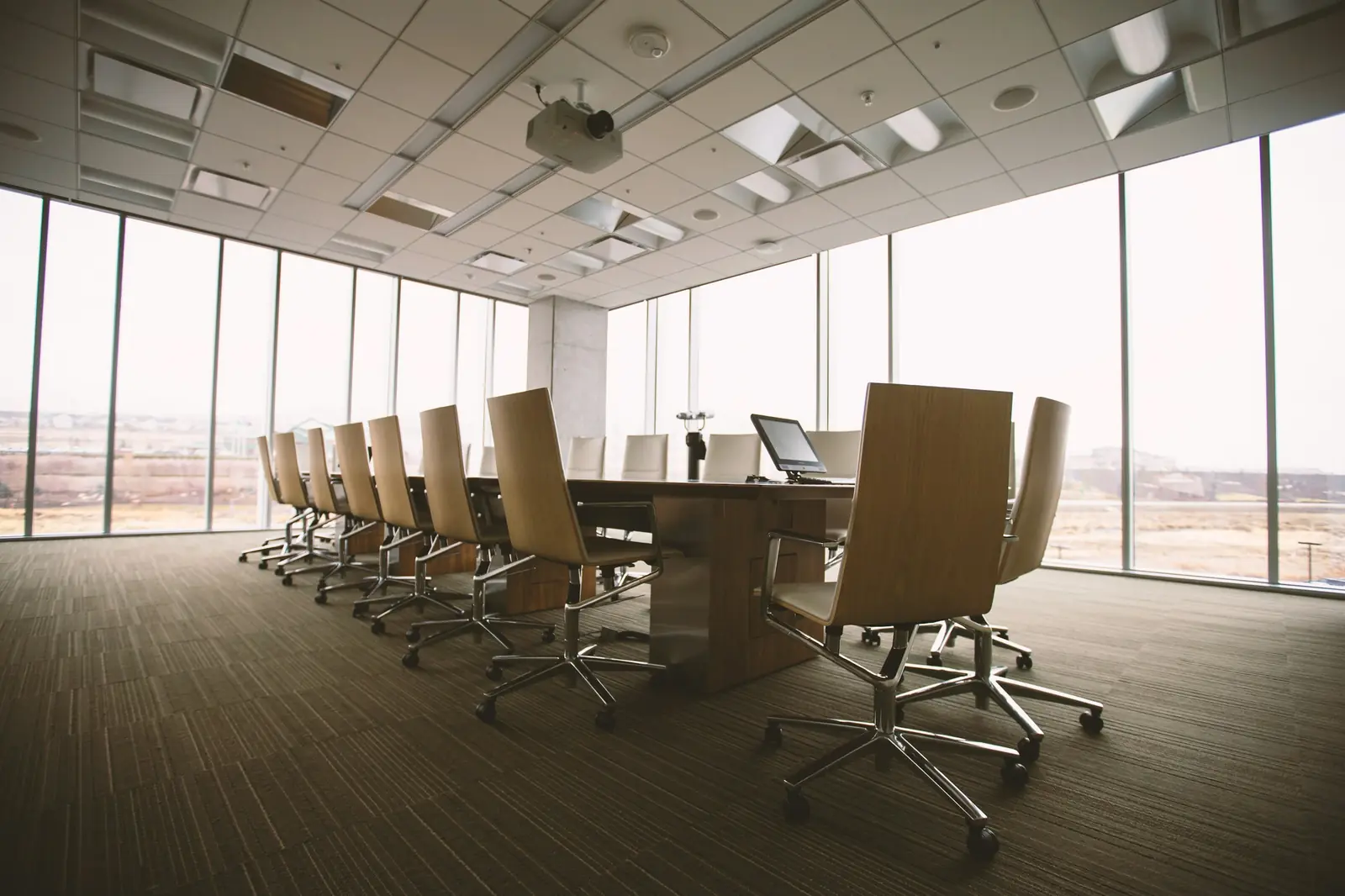 A long conference table and chairs beside a glass wall