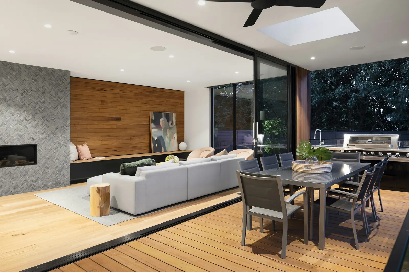 An open living room with glass walls onto a timber deck